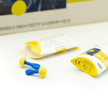 Gehörschutzstöpsel in blau/gelb neben der Verpackung