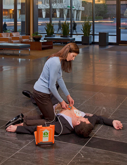 Eine frau die einen mann mit einem defibrillator wiederbelebt